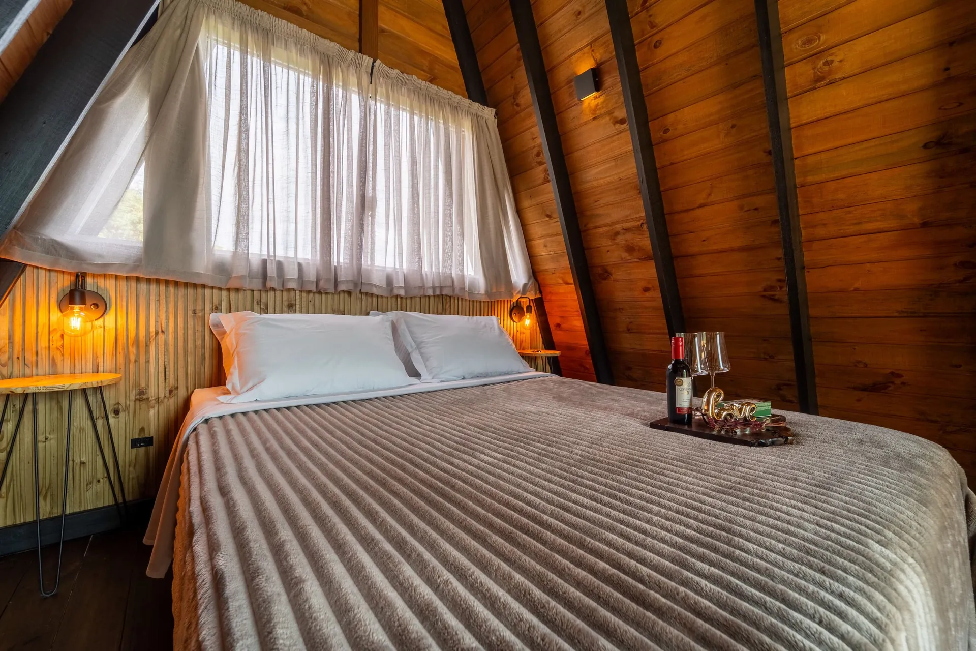 Cama de casal com manta listrada sob o telhado em A