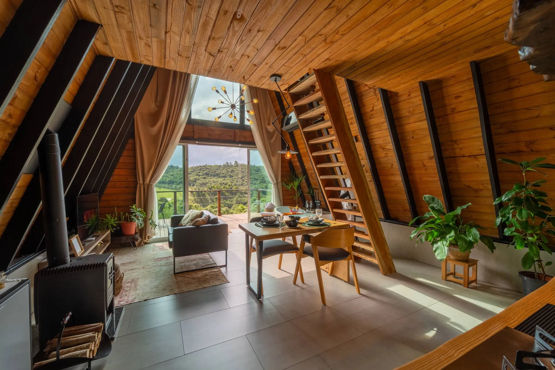 Sala integrada com lareira, mesa de jantar e a janela alta para o verde